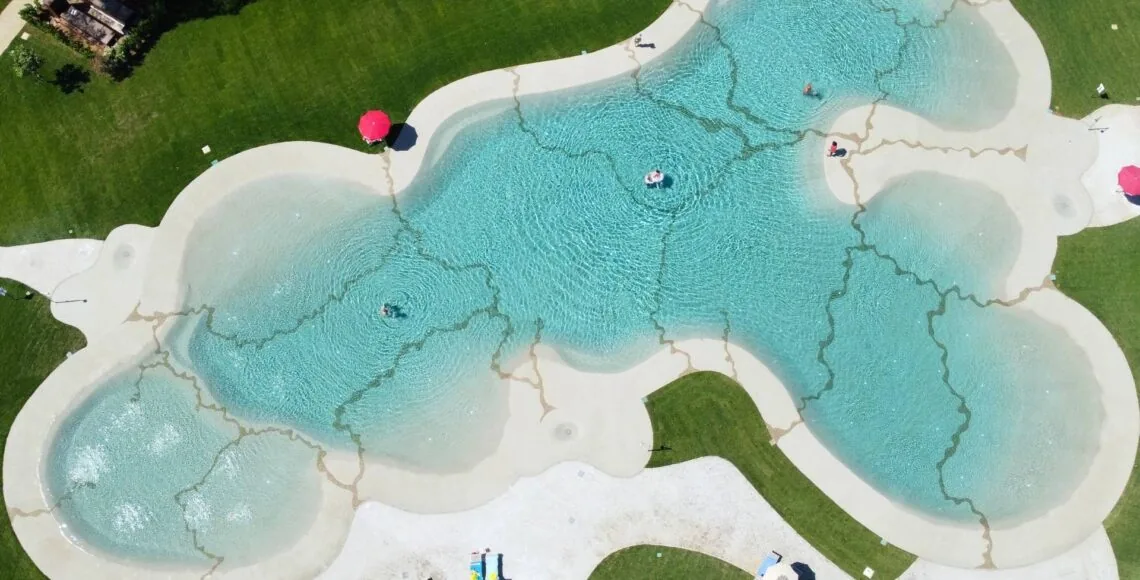 Aerial view of an organic, freehand-drawn beach-style pool in a lawn